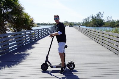 A happy rider enjoying an electric surfboard ride near a sunny beach with palm trees.