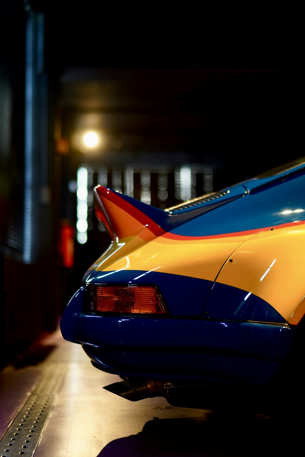 a blue and yellow car parked in a garage