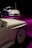 Two sleek white cars are showcased, positioned on a glossy purple floor. The foreground features a close-up of one car's side, highlighting its intricate wheel design. In the background, a second car is seen, adding depth to the scene with a dark ambient setting enhancing the vehicles.
