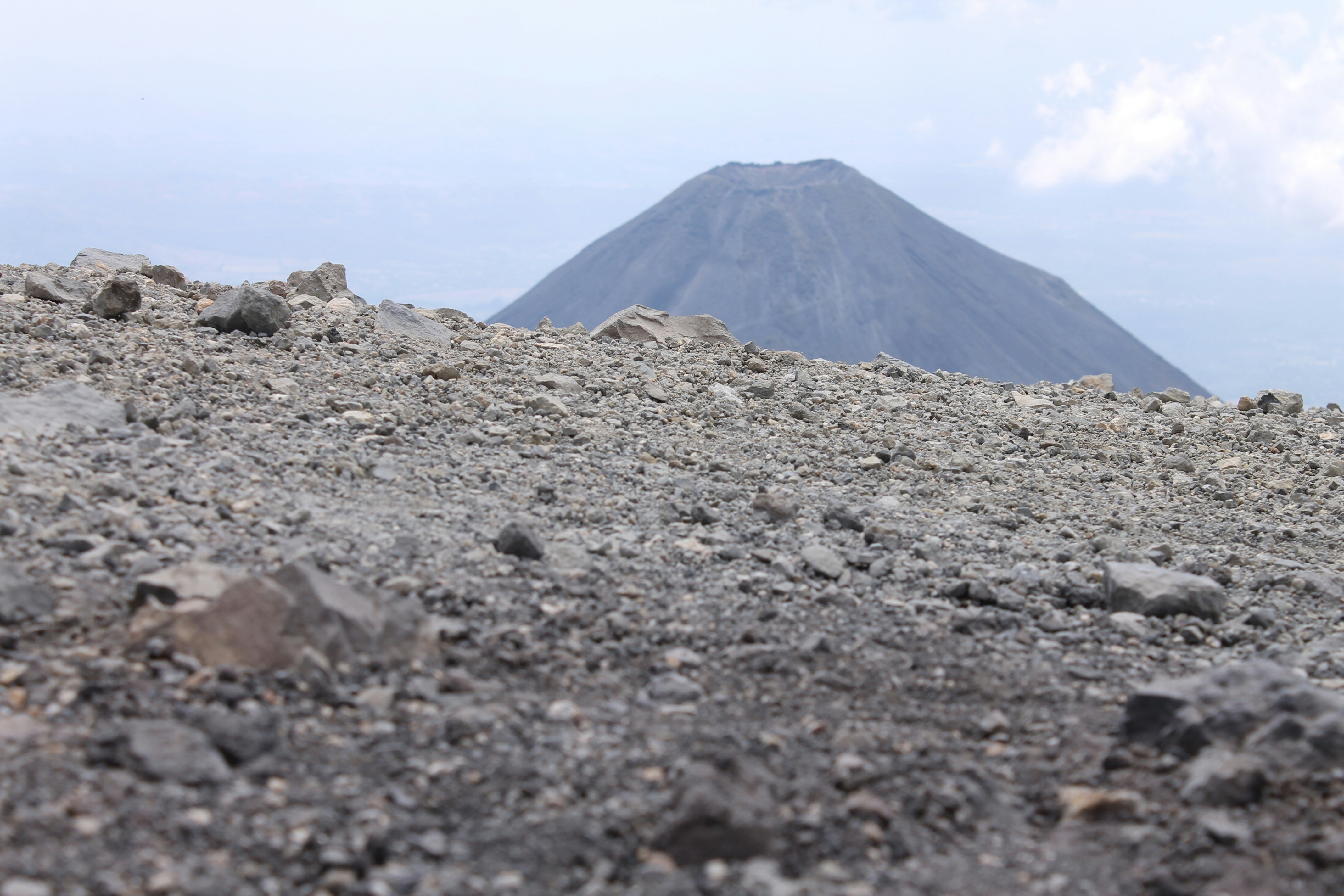 a rocky area with a mountain in the background, Izalco volcano seen from the the top of Ilamatepec volcano.