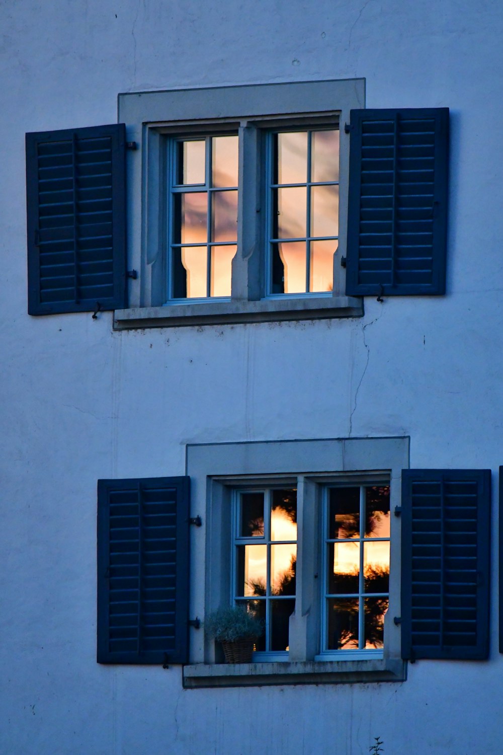 two windows with blue shutters and a sky in the background