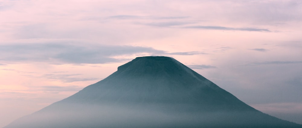 a very tall mountain in the middle of a cloudy sky