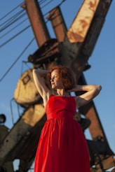 a woman in a red dress standing in front of a crane