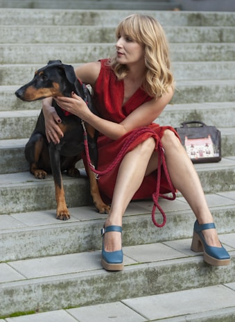 A chic outdoor scene showing a woman and her dog dressed in matching elegant bow ties and hair accessories in muted, classy colors.
