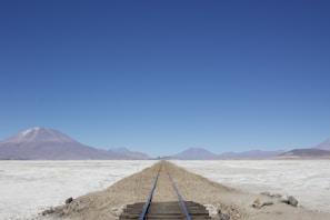 Railway tracks stretching into the horizon through a desert landscape in Mexico