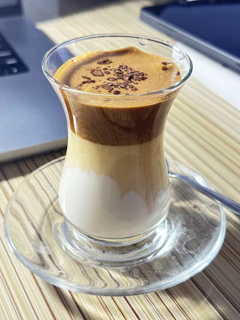 A beautifully arranged café-style drink with colorful layers and a sprinkle of cocoa powder on top.