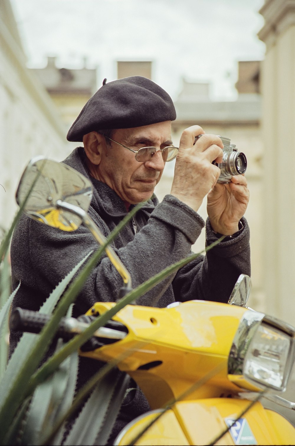 a man sitting on a yellow scooter taking a picture