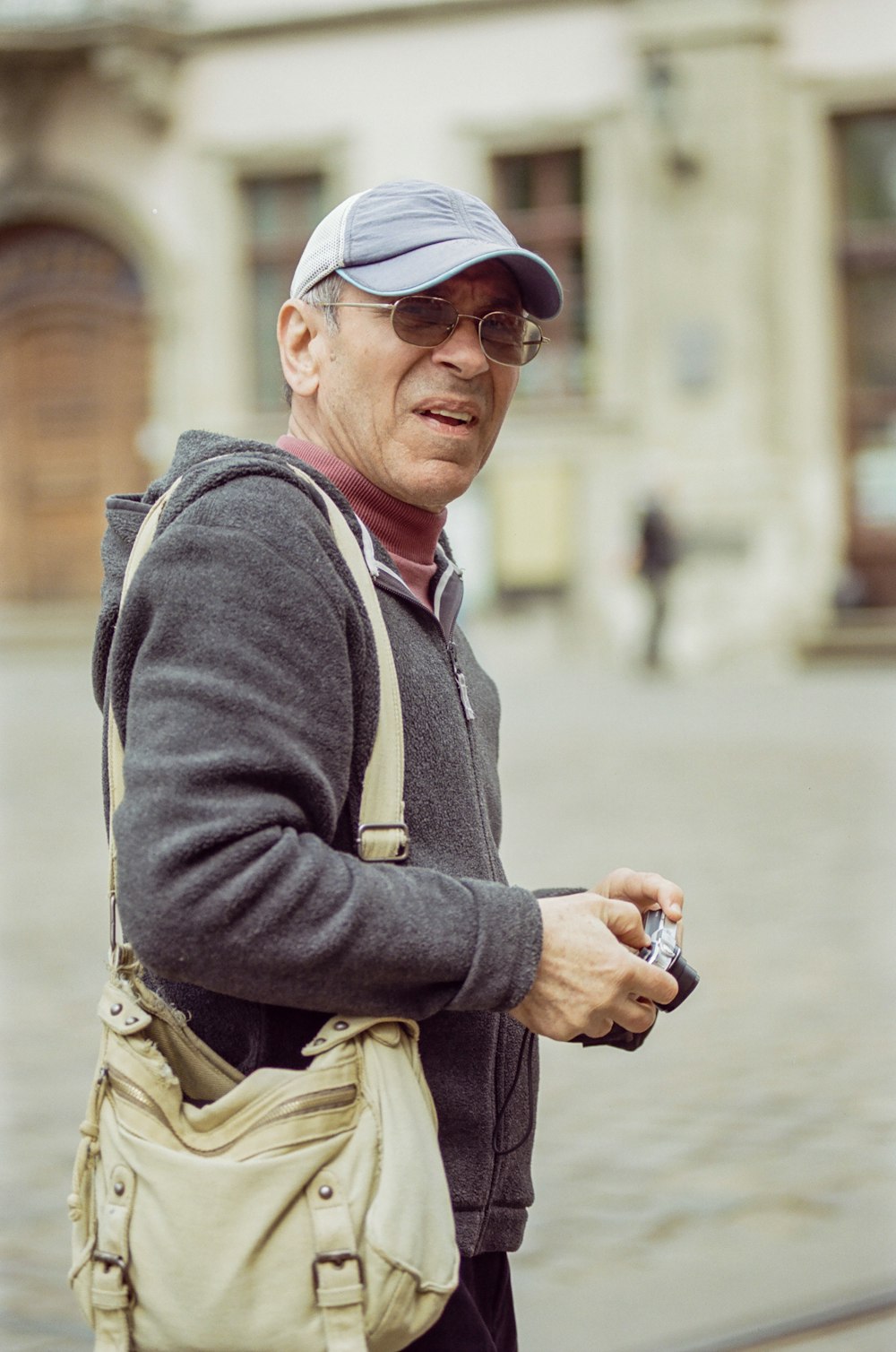 a man with a hat and glasses is looking at his cell phone