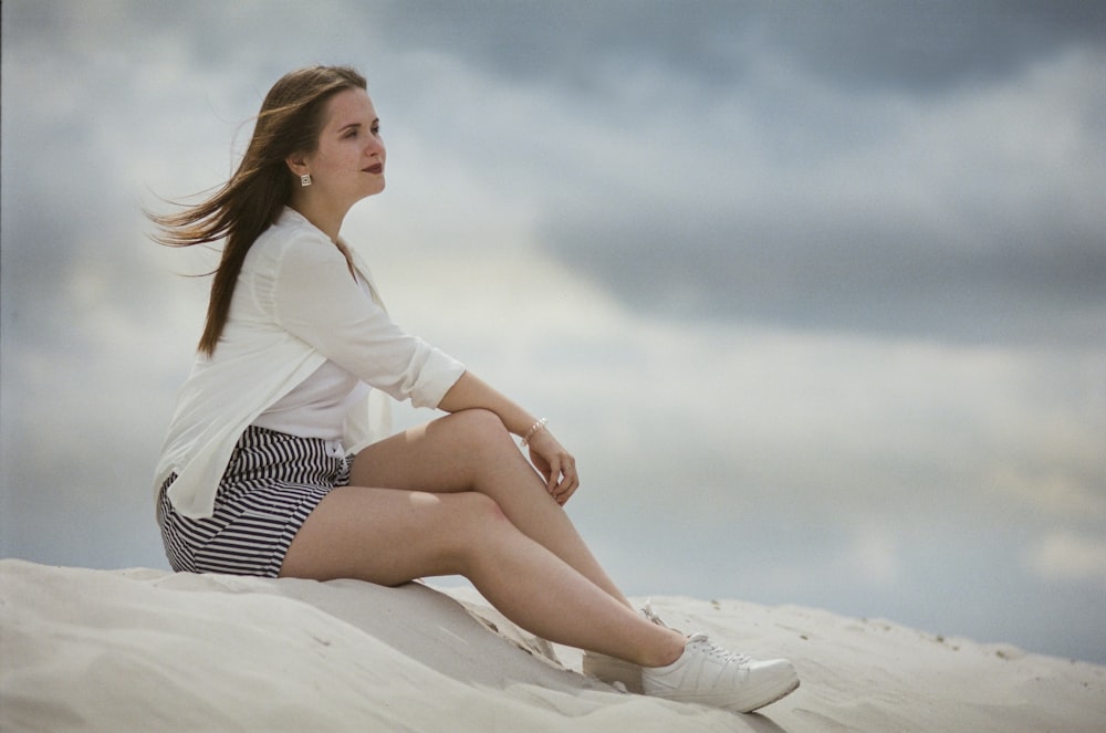 a woman sitting on top of a sandy beach