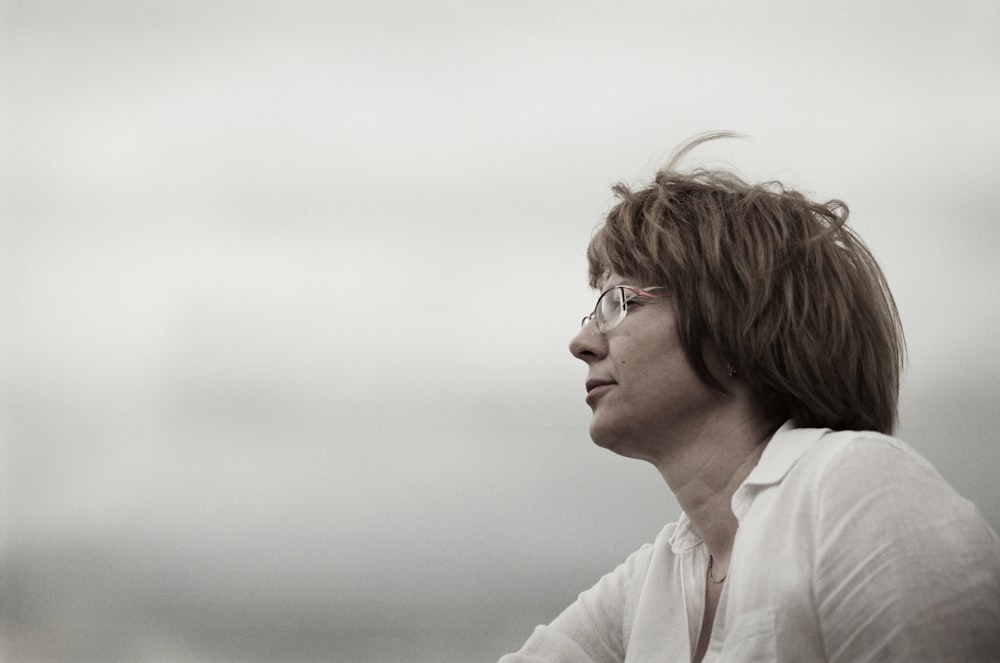 a woman with glasses looking off into the distance