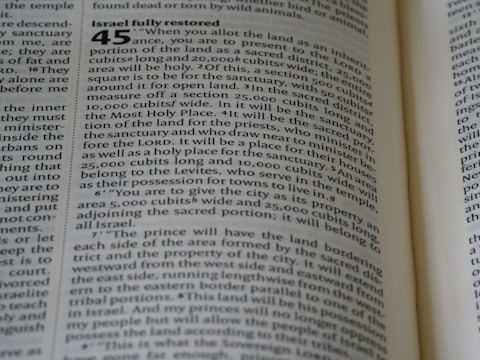 A close-up of an open book with text printed on its pages. The text includes a numbered heading and detailed information organized in paragraphs. The visible text is discussing the allocation of land. The title 'Israel fully restored' is prominent.