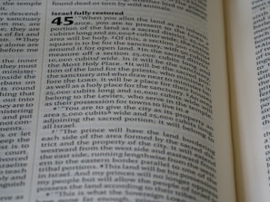 A close-up of an open book with text printed on its pages. The text includes a numbered heading and detailed information organized in paragraphs. The visible text is discussing the allocation of land. The title 'Israel fully restored' is prominent.