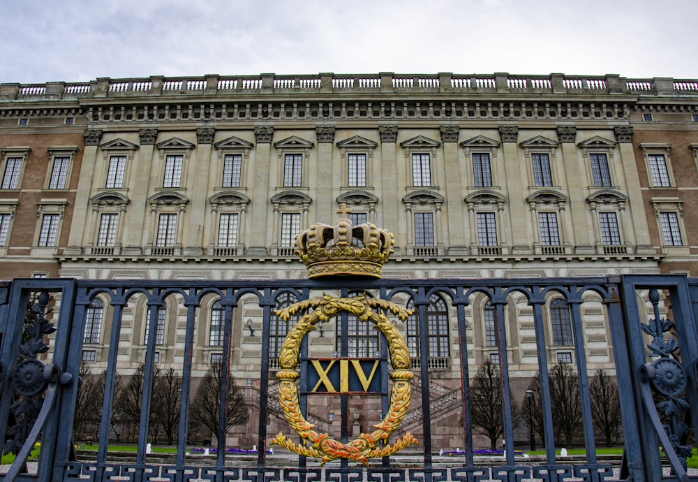 a gate with a crown on it in front of a building