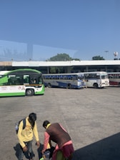 A bus driver assisting passengers with their luggage at a busy bus station.