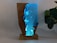 A unique decorative object made from a combination of wood and resin, illuminated with soft blue light. The resin segment mimics a watery scene with embedded figures that resemble divers or swimmers, creating an underwater effect. The natural grain and texture of the wood contrast strikingly with the translucent blue resin. Positioned on a wooden base, the piece exudes a modern and artistic vibe.