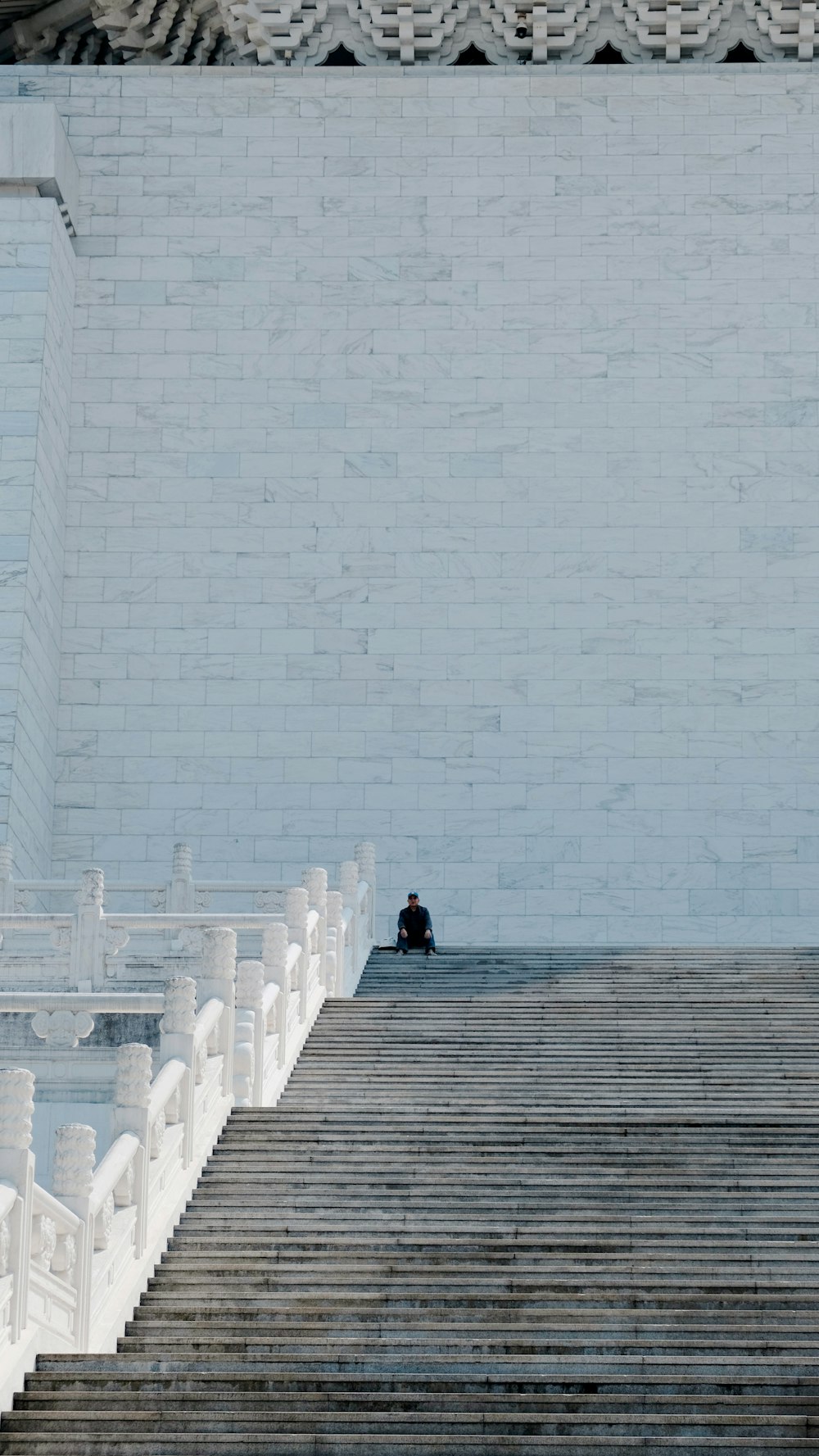 a person sitting on a bench in front of a wall