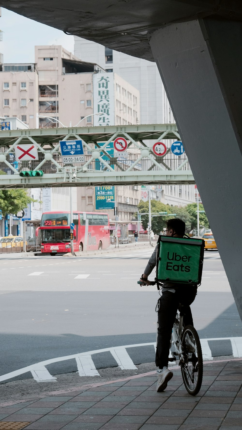 a man riding a bike down a street under a bridge