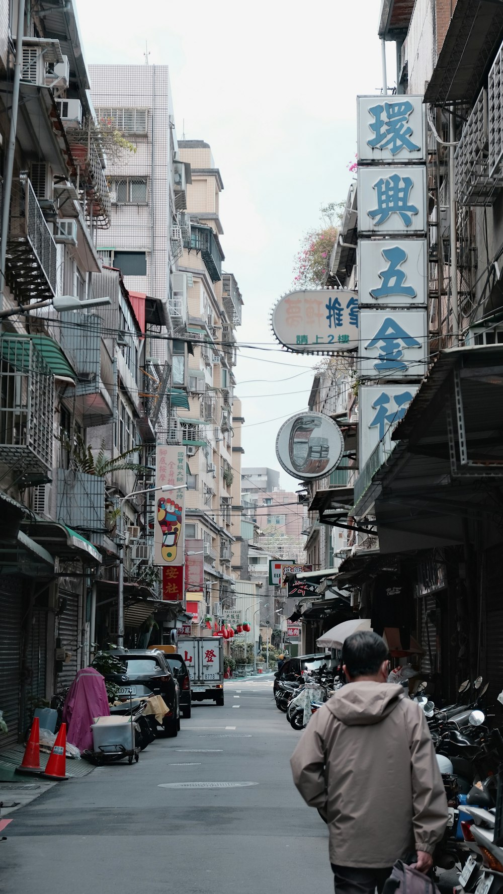 a man walking down a street next to tall buildings