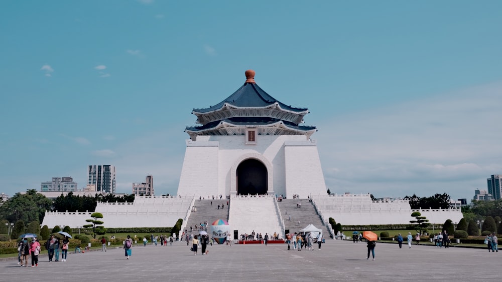 a group of people walking around a large white building