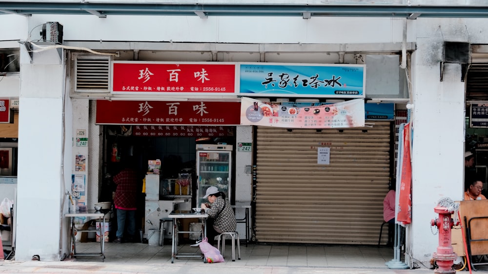 a person sitting at a table in front of a store