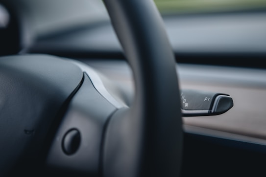 Close-up of a car's steering wheel and a control lever, with smooth leather texture and blurred background for an elegant effect.