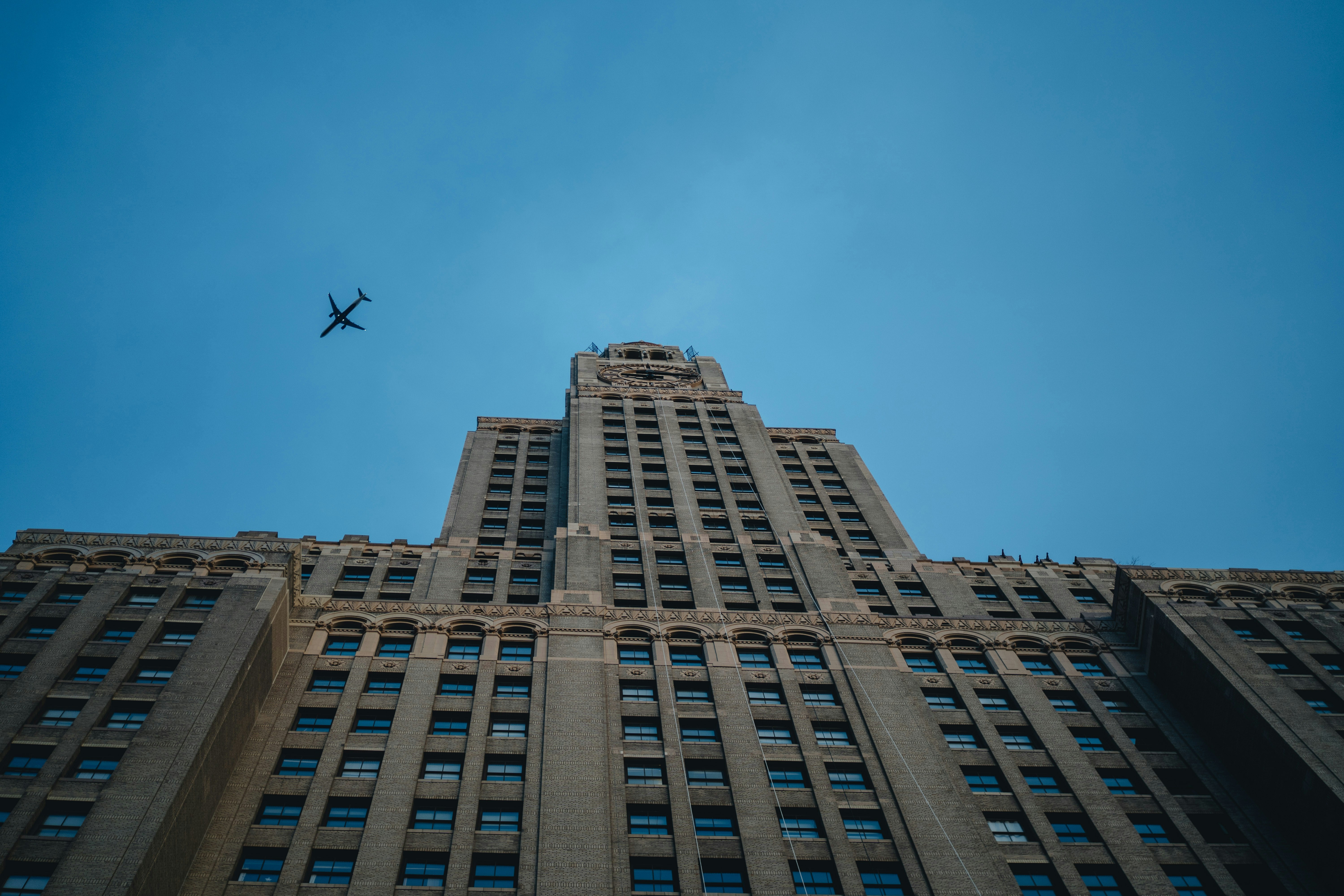 un avión volando en el cielo sobre un edificio alto