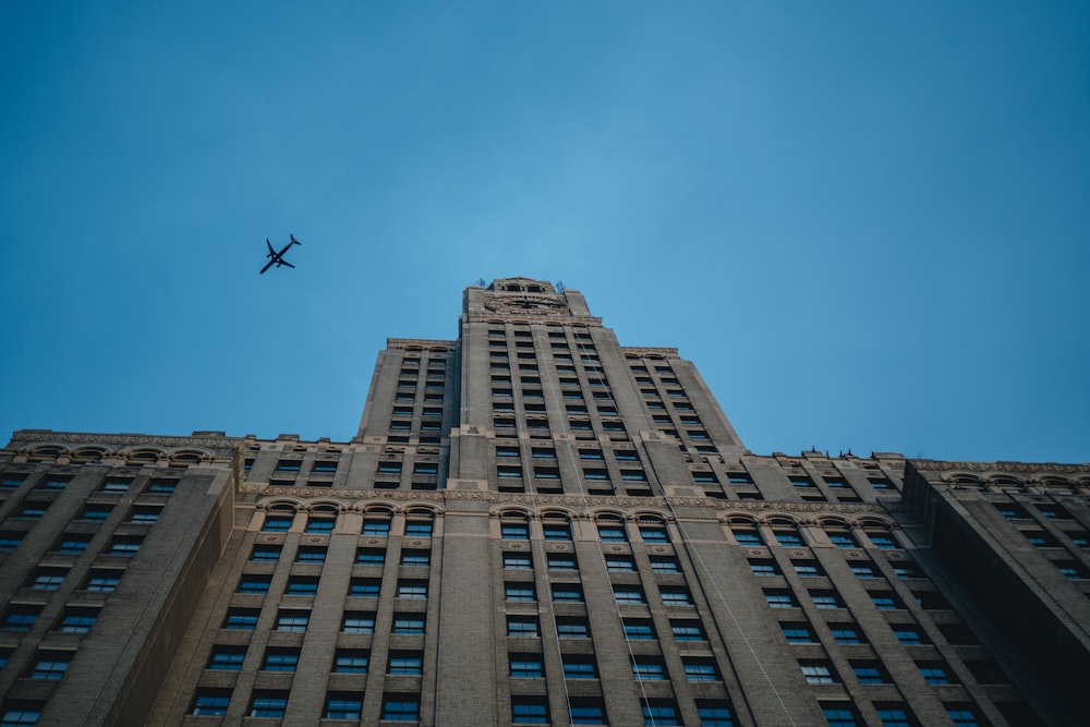an airplane flying in the sky over a tall building