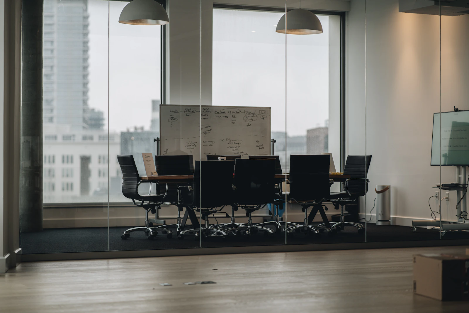 A glass-walled conference room with a long table overlooking the city
