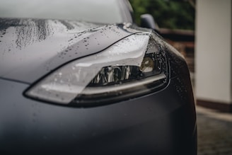 a close up of a car's headlight on a rainy day