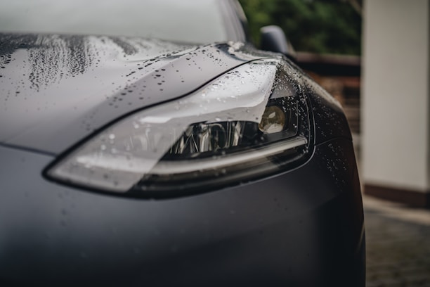 a close up of a car's headlight on a rainy day