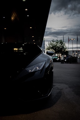 A sleek sports car with a custom exhaust system glowing under city lights at dusk.