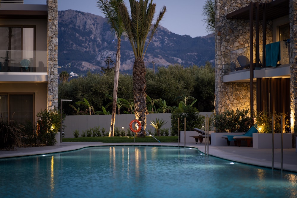 a swimming pool surrounded by palm trees in front of a building