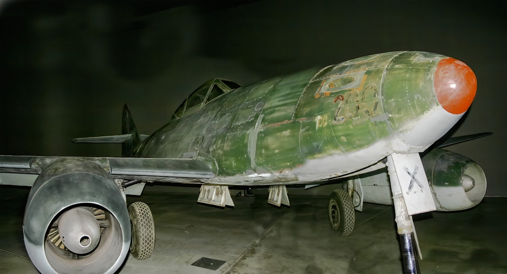 a green and white fighter jet sitting on top of a cement floor