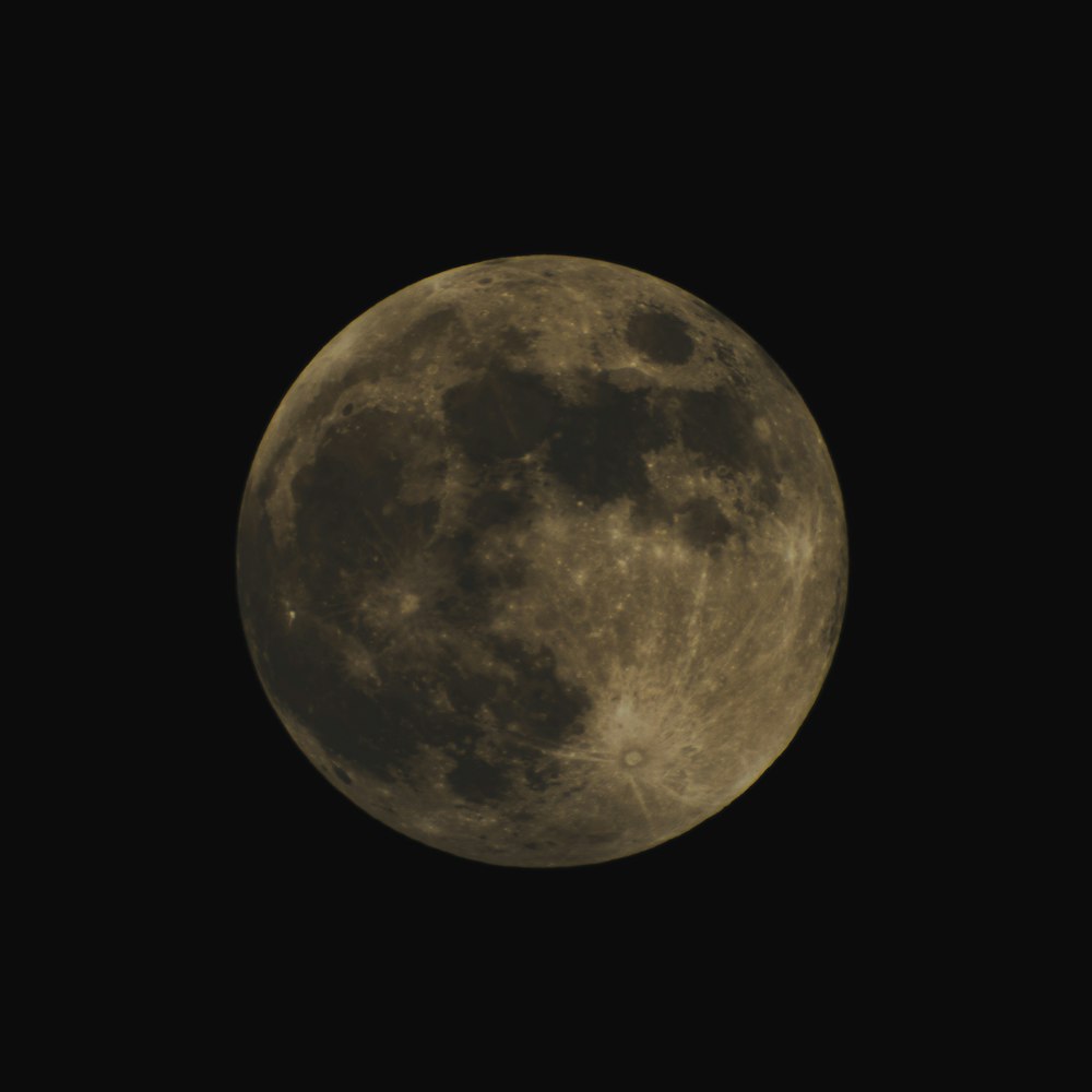 a full moon is seen in the dark sky