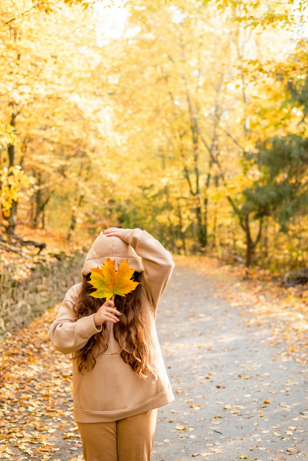 a woman walking down a leaf covered road