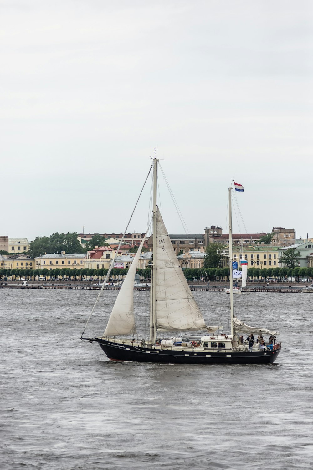 a sailboat in a body of water with buildings in the background