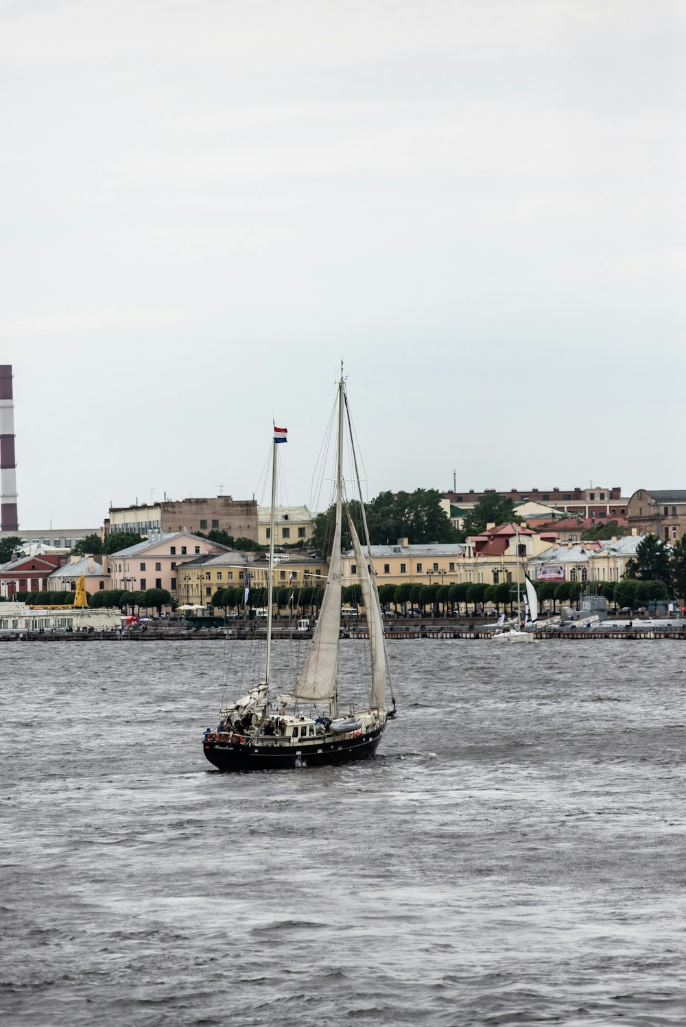 a sailboat in a body of water with a city in the background