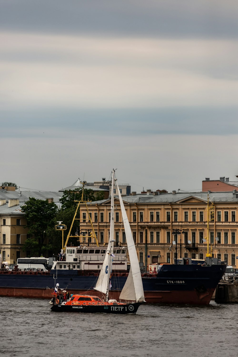 a sailboat in a body of water with a large building in the background