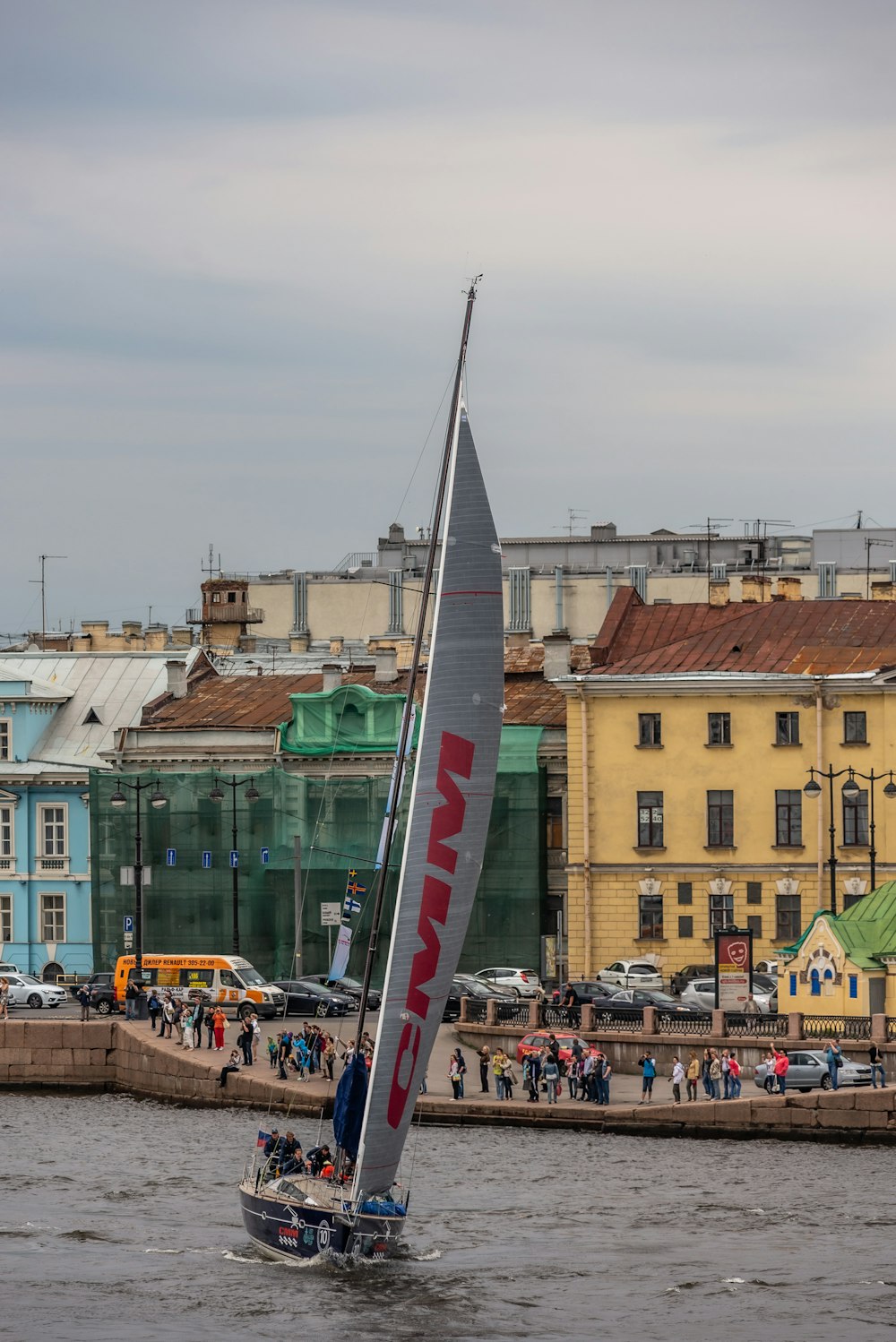 a sailboat in a body of water with buildings in the background