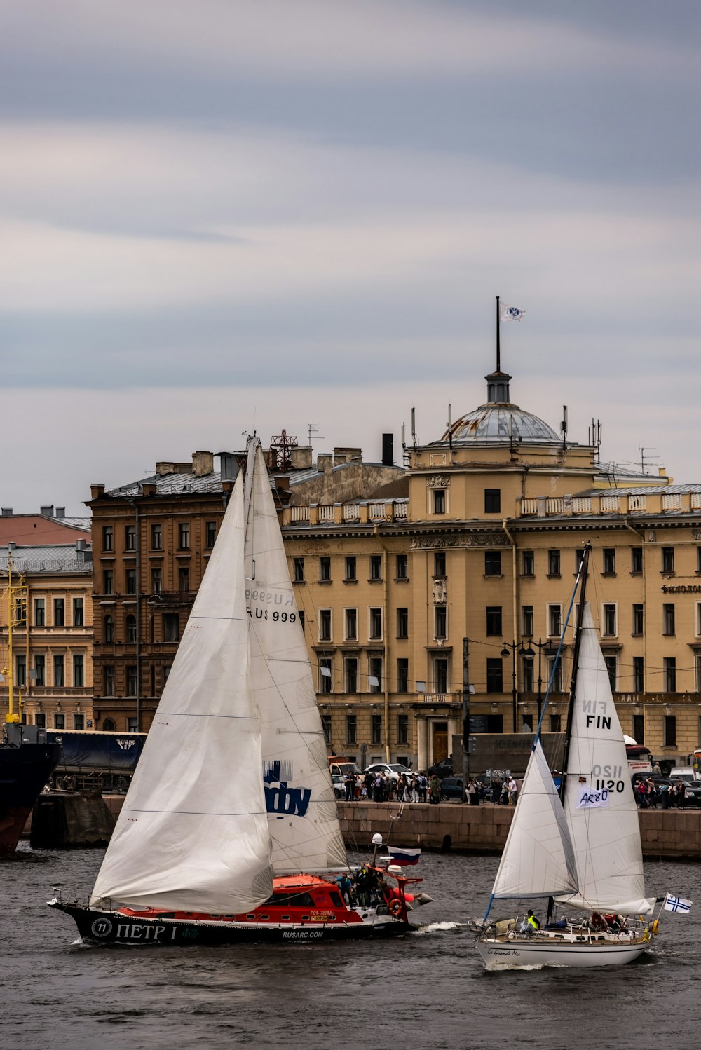 two sailboats in the water in front of a large building