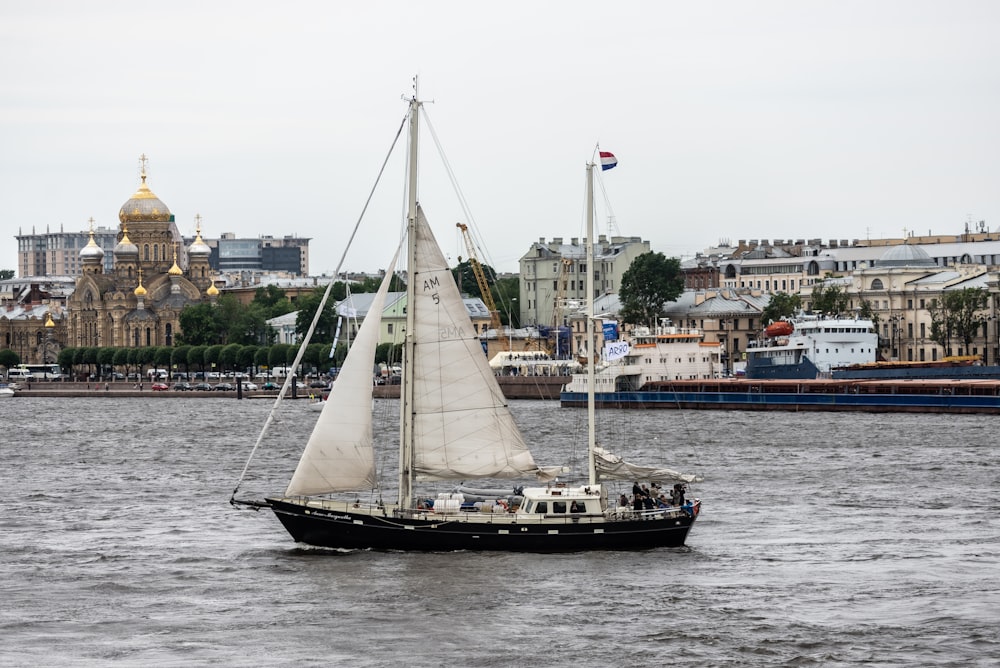 a sailboat in a body of water with a city in the background