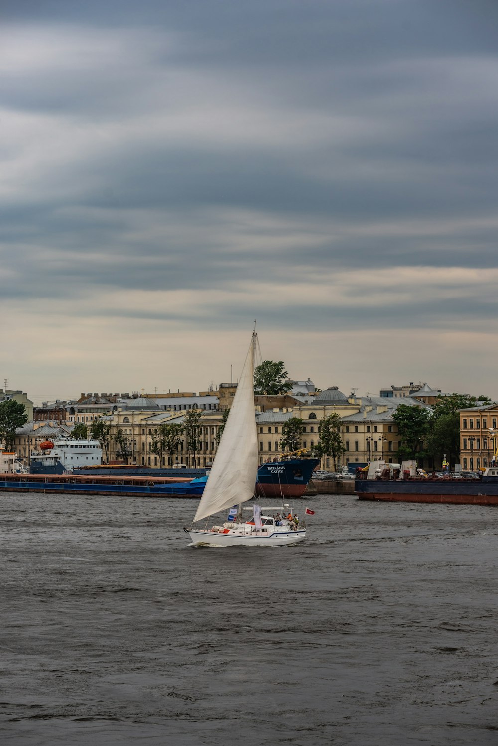 a sailboat on the water with a city in the background