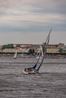 A sailboat navigating through choppy seas under a cloudy sky.