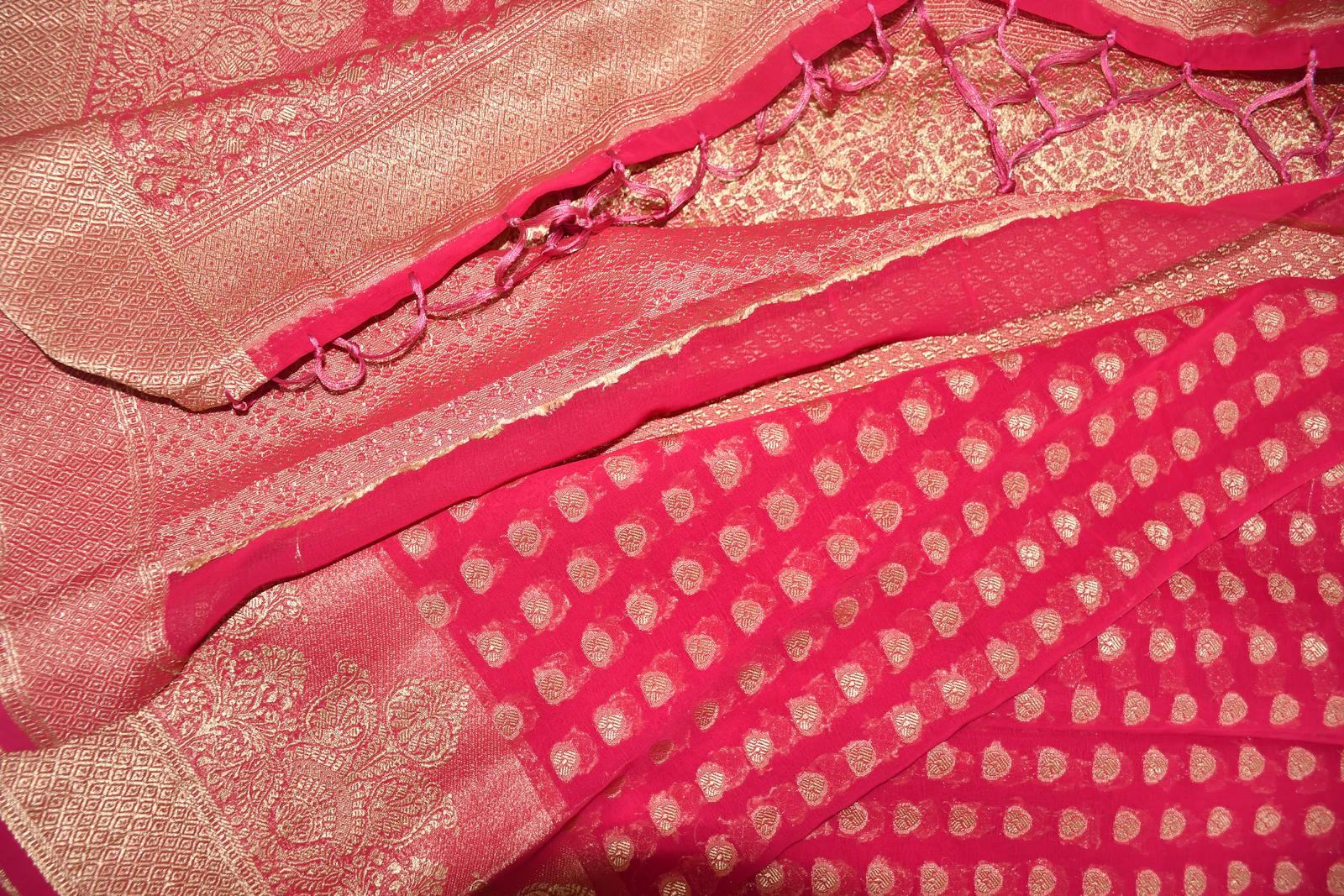 Close up of a pink and gold silk saree with zari work