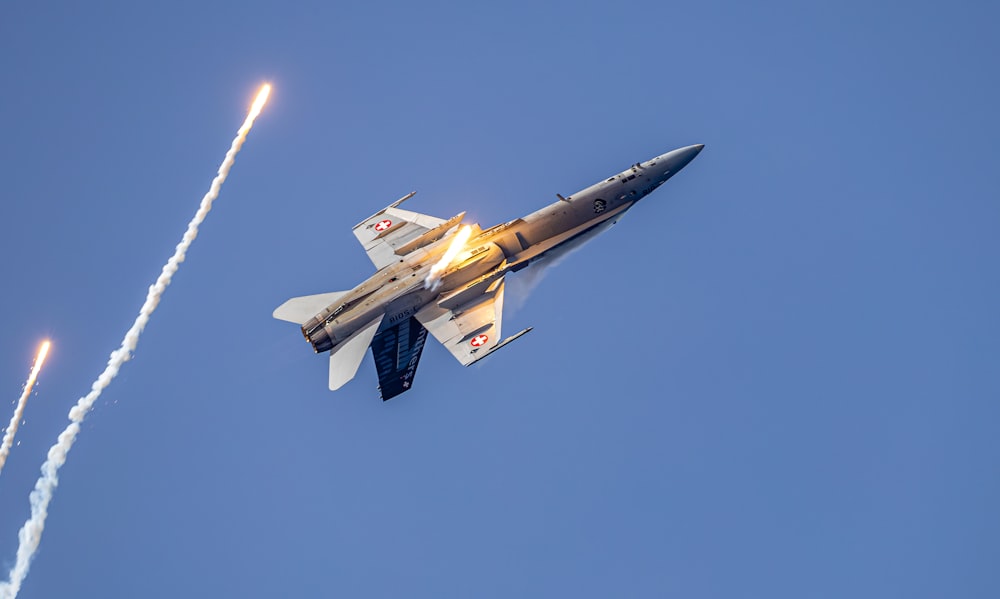 a fighter jet flying through a blue sky