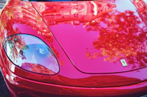 Close-up of a high-end sports car’s glossy finish reflecting ambient light inside a premium transport vehicle.
