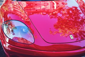 Side view of a red sports car with a mirror-like finish reflecting the surroundings.