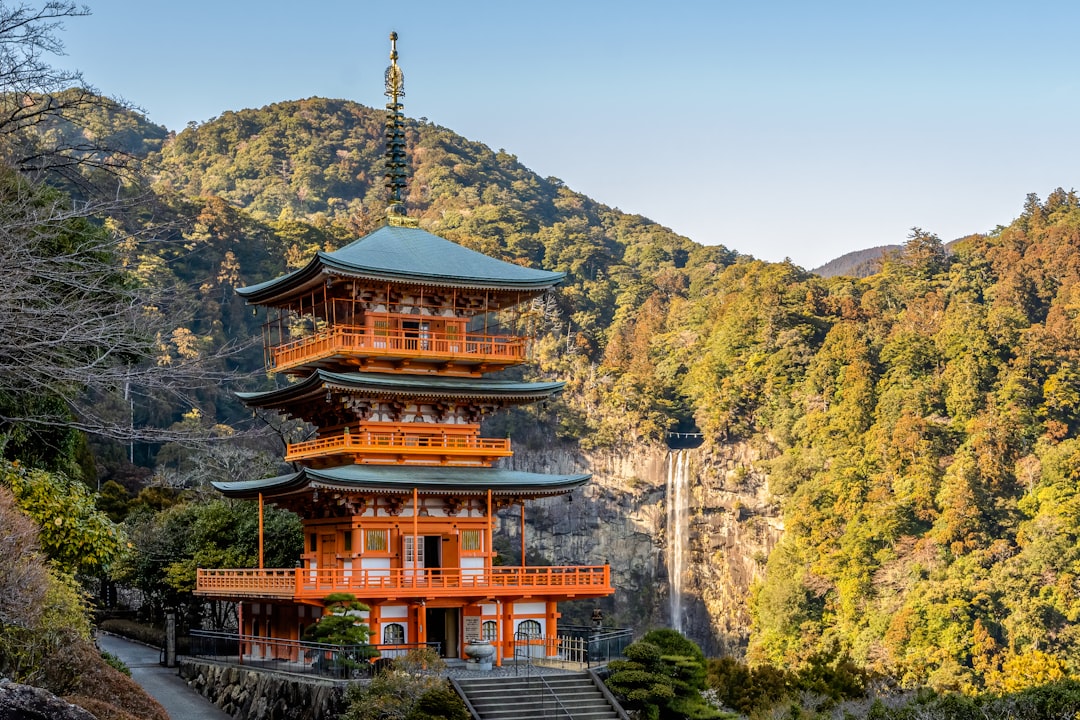 a tall building sitting on top of a lush green hillside, This is the wonderful three-storied pagoda of Seiganto-ji templ