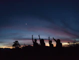 A sunset view with silhouettes of people celebrating progress together.
