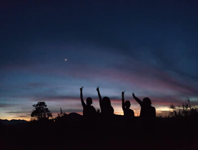 A sunset view with silhouettes of people celebrating progress together.